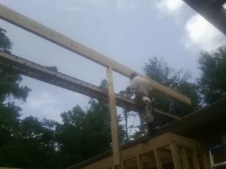 Carpenter setting a ridge beam over a new addition frame — Ice Dam Removal by Roofing Brothers in Newbern