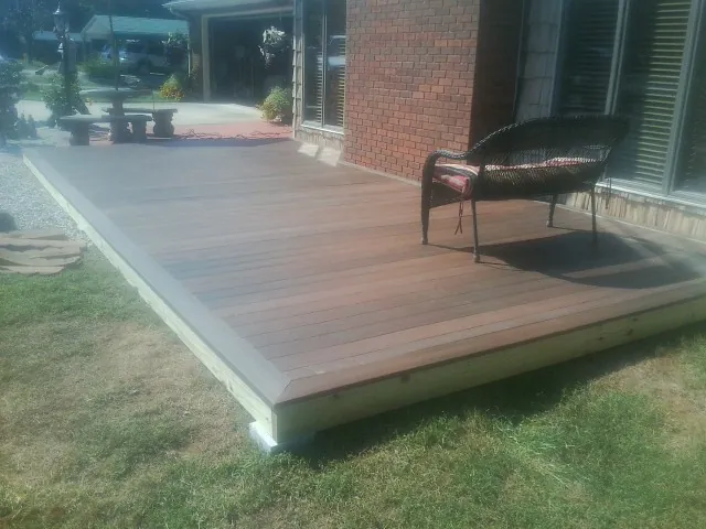 New wood deck and wicker chair beside a brick house in Newbern